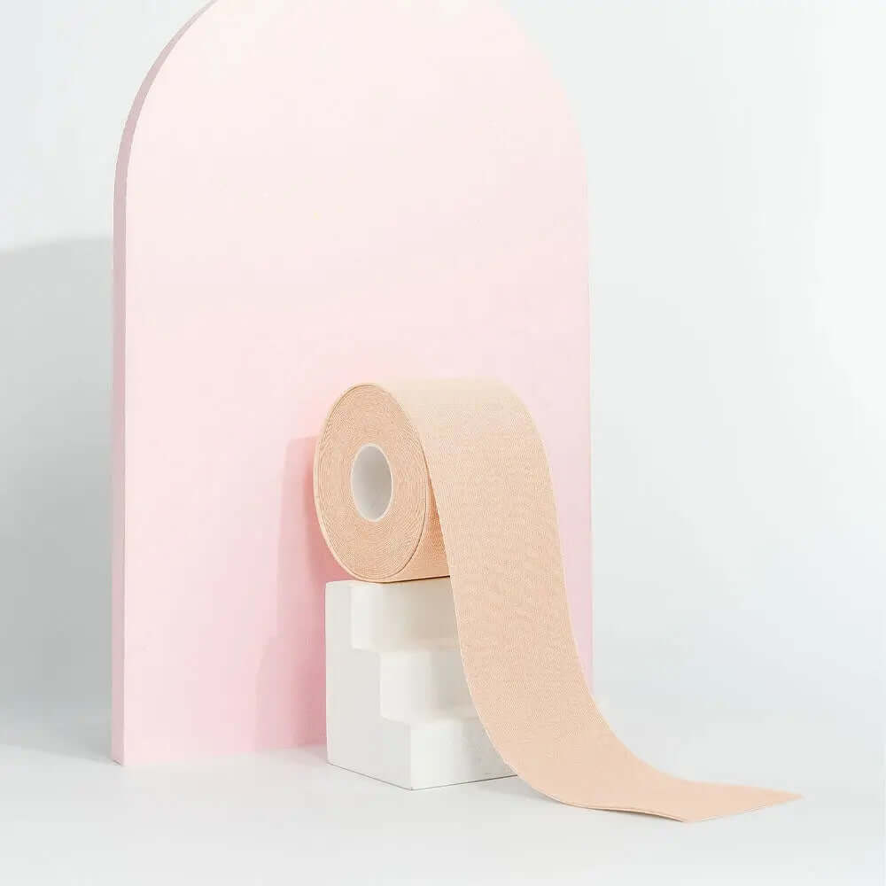 Brushworks Body Tape roll on a white pedestal with a pink background, designed for instant lift and maximum hold.