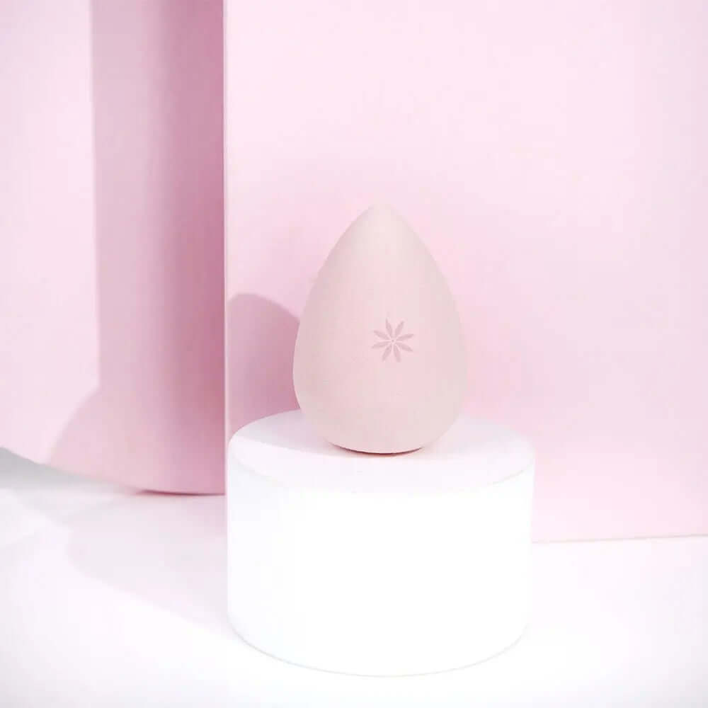 Brushworks Complexion Sponge on a white pedestal against a pink backdrop, ideal for applying liquid and powder makeup.