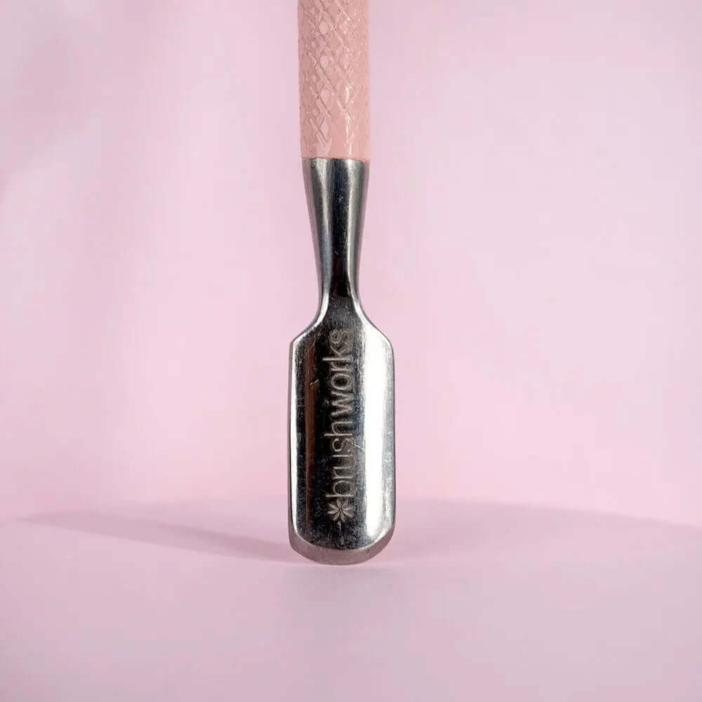 Brushworks dual-end cuticle pusher showcasing the curved spoon end for shaping and pushing cuticles.
