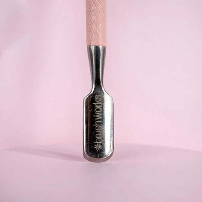 Brushworks dual-end cuticle pusher showcasing the curved spoon end for shaping and pushing cuticles.