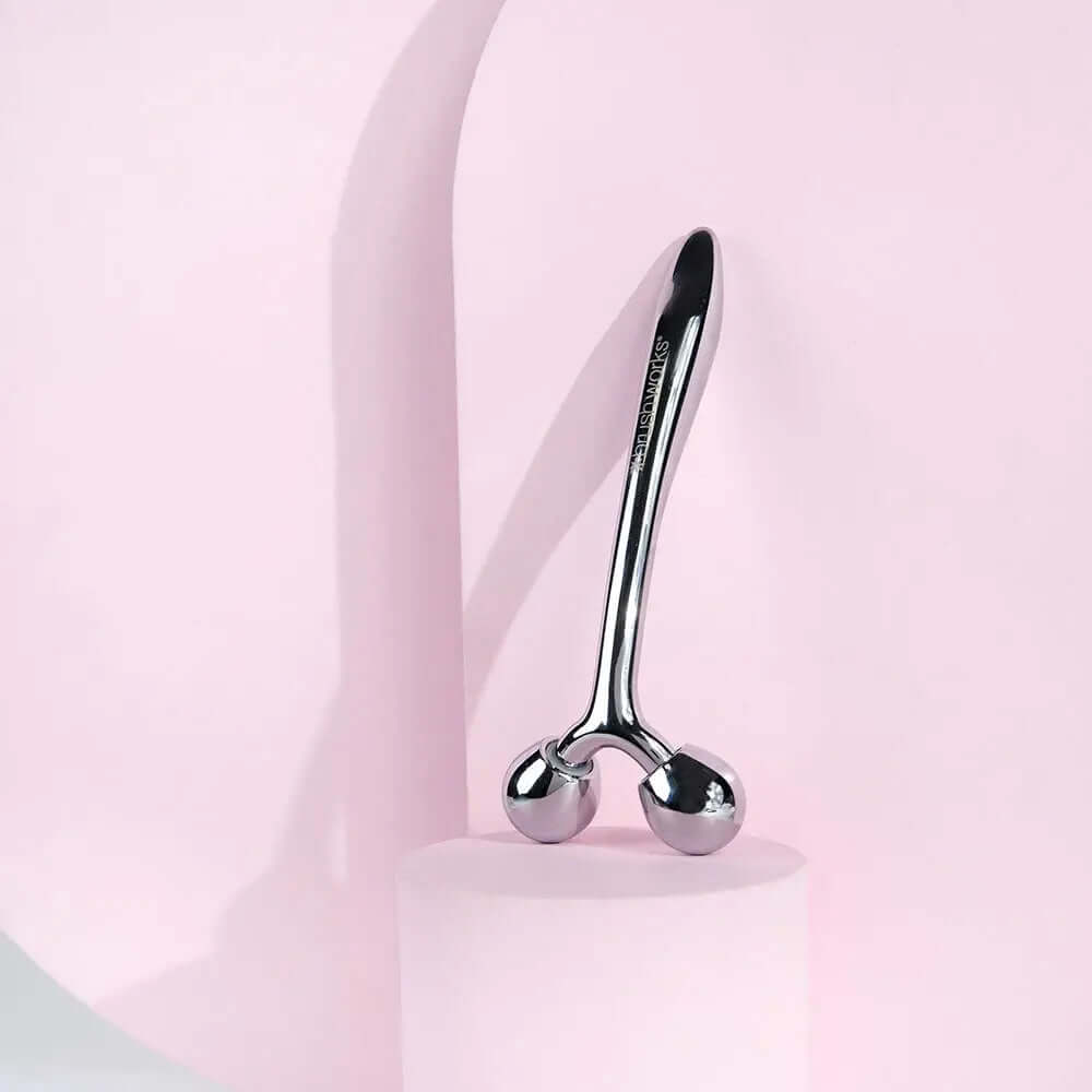 Brushworks Face Sculpting Zinc Roller on a pink background, perfect for facial massage and skin toning.