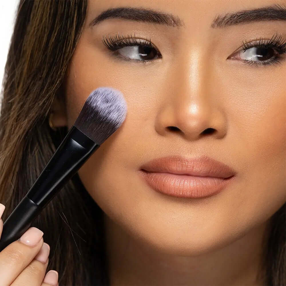Model using Brushworks Foundation Brush for smooth, even makeup application on the face.