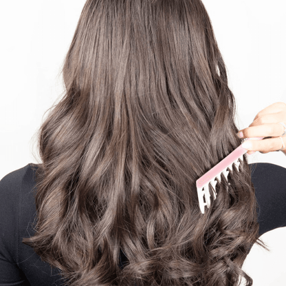 Woman using Brushworks Smoothing Curl Comb to create defined, bouncy curls in her long, wavy hair.