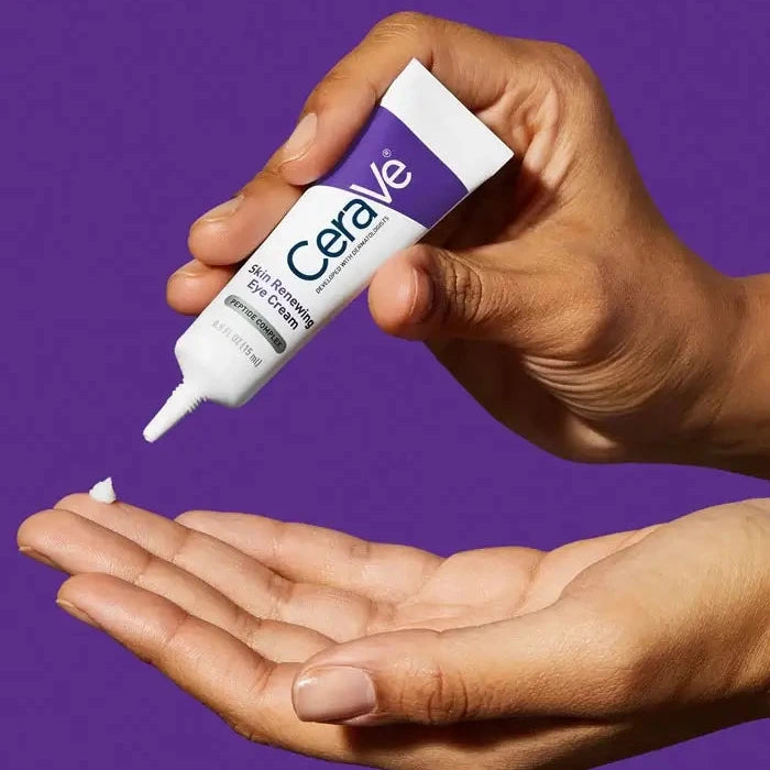 Hand dispensing CeraVe Skin Renewing Eye Cream with Peptide Complex from tube against purple background