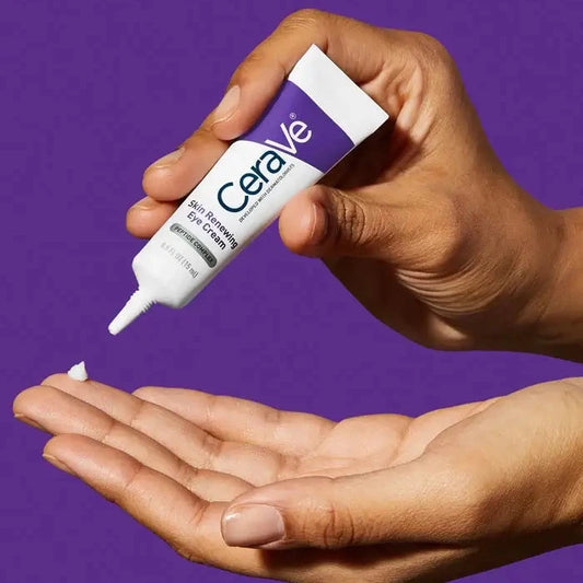 Hand dispensing CeraVe Skin Renewing Eye Cream with Peptide Complex from tube against purple background