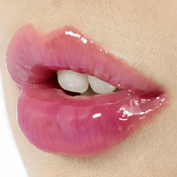 Close-up of full lips coated with shiny, glossy Charlotte Tilbury Lip Lustre in Pillow Talk, showcasing a nude-pink hue.
