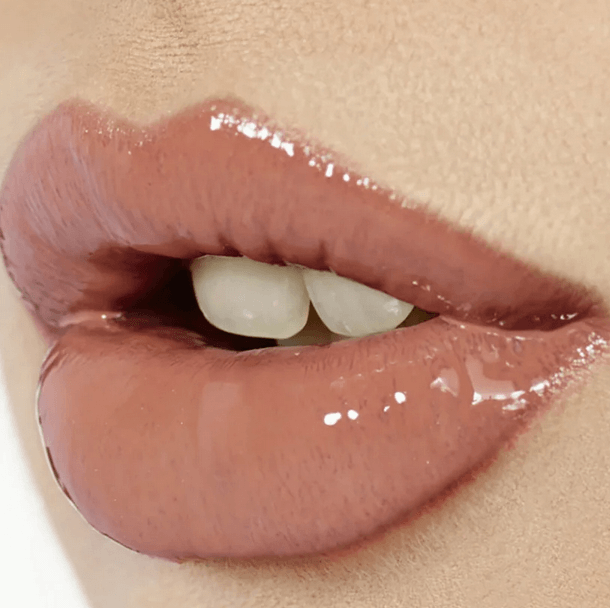 Close-up of lips wearing Charlotte Tilbury Lip Lustre in Pillow Talk, showcasing a glossy nude-pink shine and plumped effect.