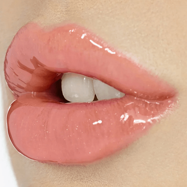 Close-up of glossy nude-pink lips enhanced with Charlotte Tilbury Lip Lustre for a radiant, plumped appearance.