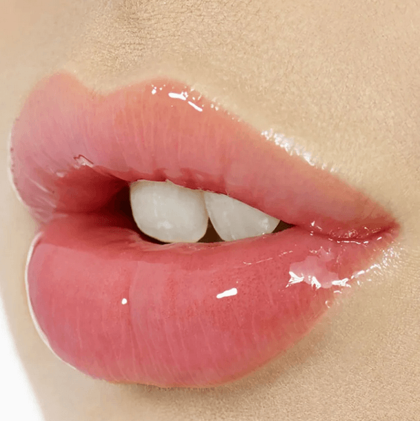 Glossy lips enhanced with Charlotte Tilbury Lip Lustre in Pillow Talk, showcasing a nude-pink shine and hydrated appearance.