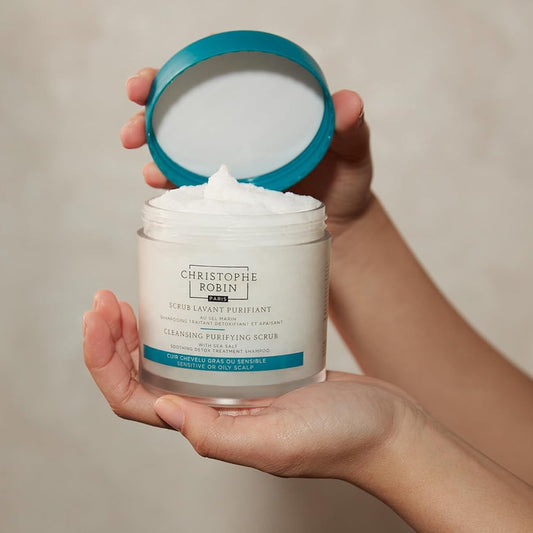 Person holding a jar of Christophe Robin hair care product with visible cream.
