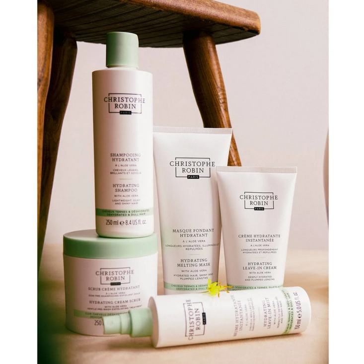 Collection of Christophe Robin skincare products on a wooden stool.