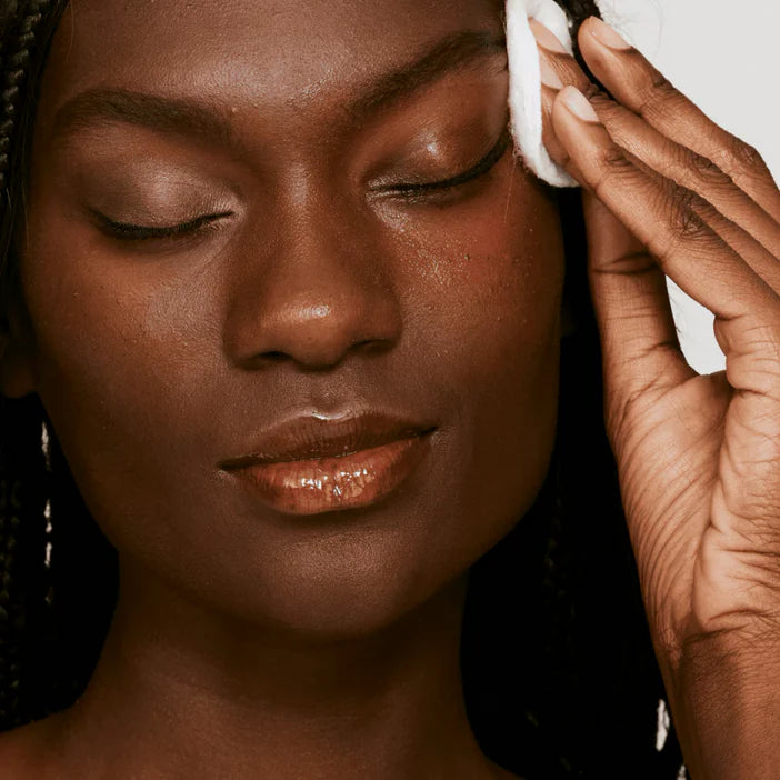 Woman cleaning her face with a CLINIQUE  white cloth, close-up of her face and hand.