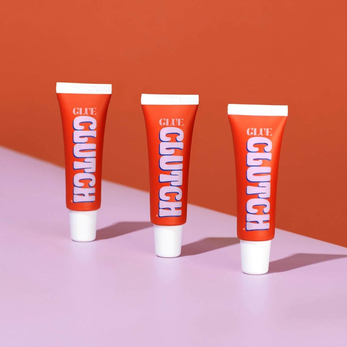 CLUTCH Glue Liquid Fashion Tape 15ml tubes on a pink and orange background, perfect for secure fashion solutions.