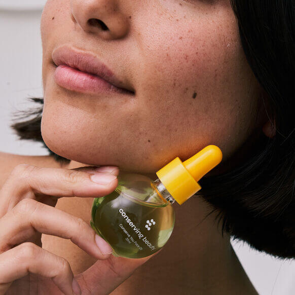 Woman applying Conserving Beauty Conserve You Face Oil for a radiant, youthful complexion.