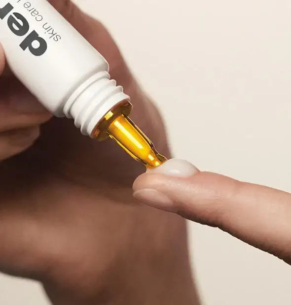 Close-up of dermalogica dropper being filled with a white bottle labeled 'der'.
