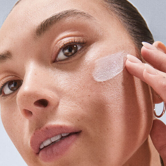 Woman applying Dermalogica Dynamic Skin Recovery SPF 50 on her face for sun protection and hydration.