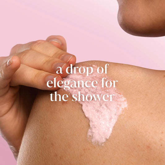 Hand applying Dove pink soap or lotion to a person's arm with a soft pink background and text 'a drop of elegance for the shower'.