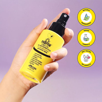 Hand holding a yellow bottle with black spray nozzle against a purple background, featuring icons for natural ingredients, vegan formula, and not tested on animals.