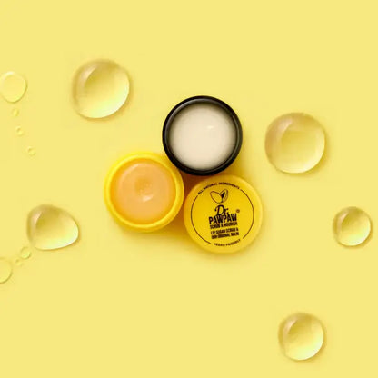 Dr. PawPaw lip balm and cream on a yellow background with clear droplets.