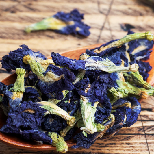 Dried blue butterfly pea flowers on a wooden spoon and surface
