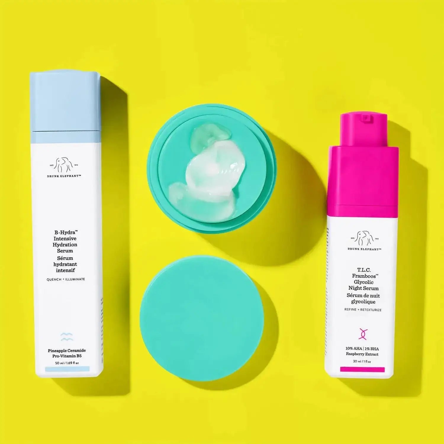 Drunk Elephant B-Hydra Serum and T.L.C. Framboos Glycolic Night Serum on vibrant yellow background.