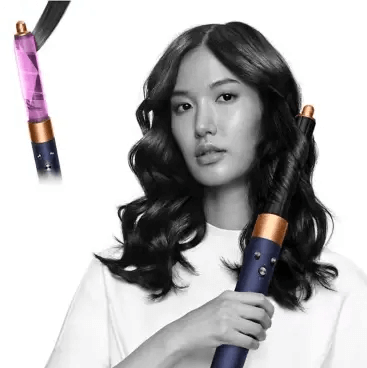 Woman holding Dyson Airwrap™ Complete Long Volumise styling tool with Coanda technology for all hair types.