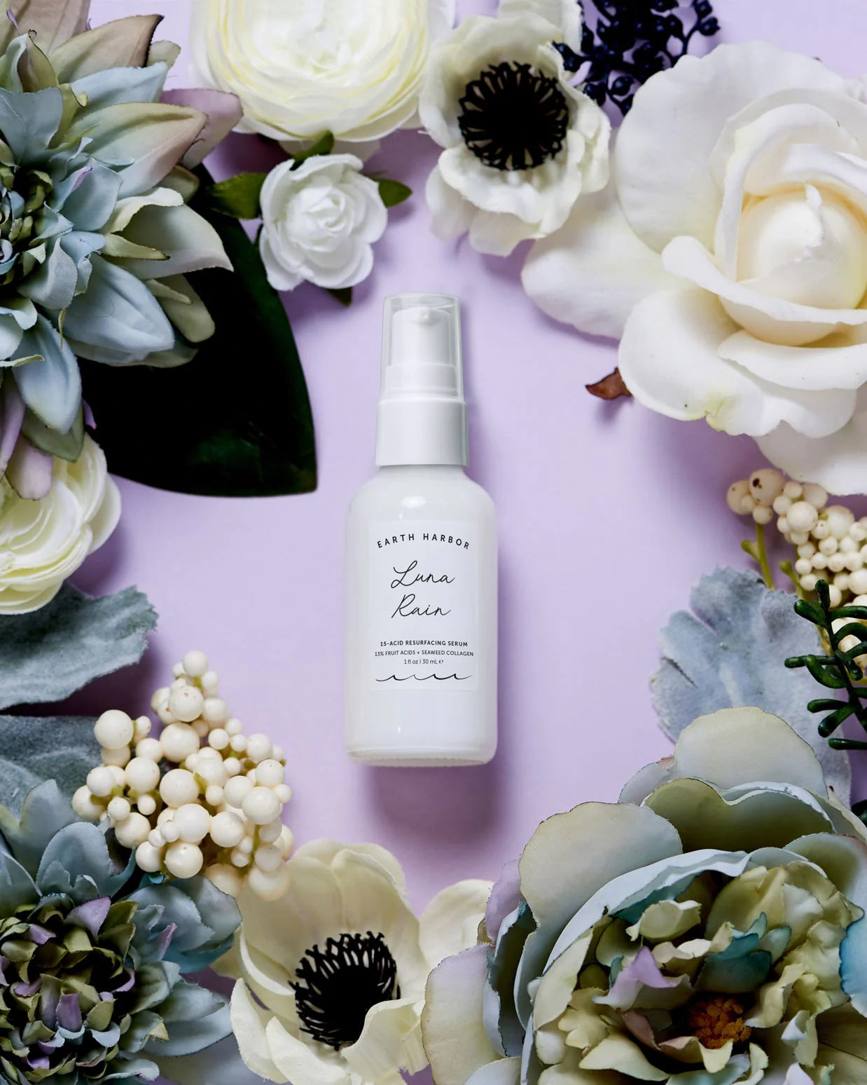 Earth Harbor White spray bottle labeled 'Lana' surrounded by flowers on a purple background