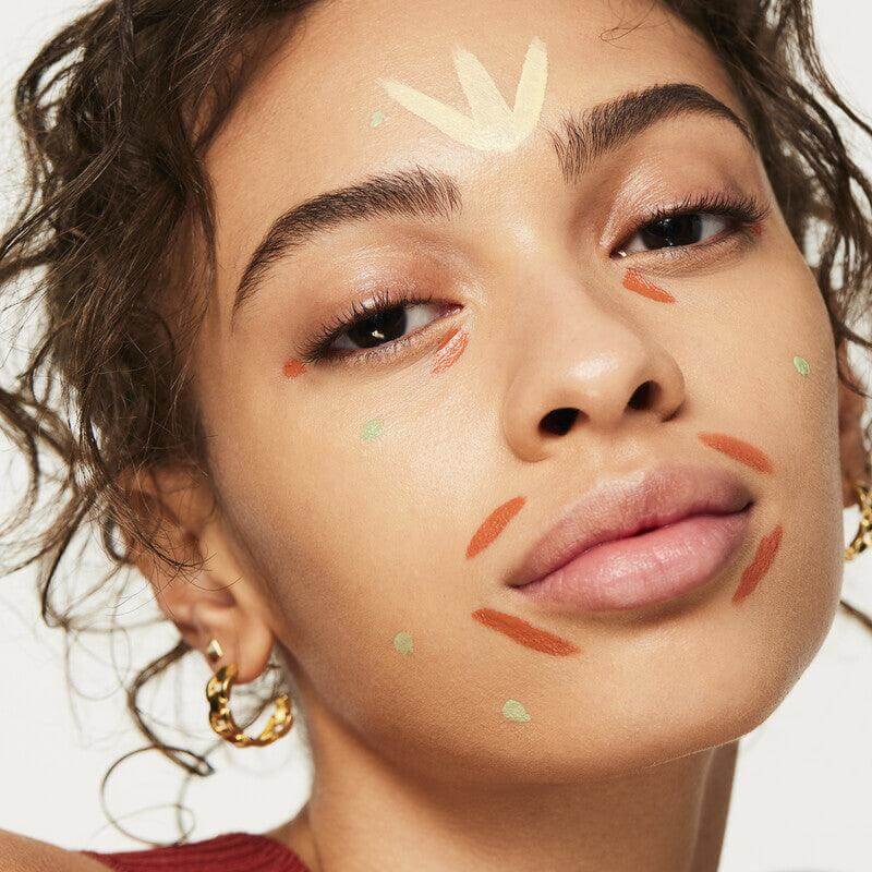 Model demonstrating e.l.f Camo Color Corrector with various shades on her face for color correction techniques.
