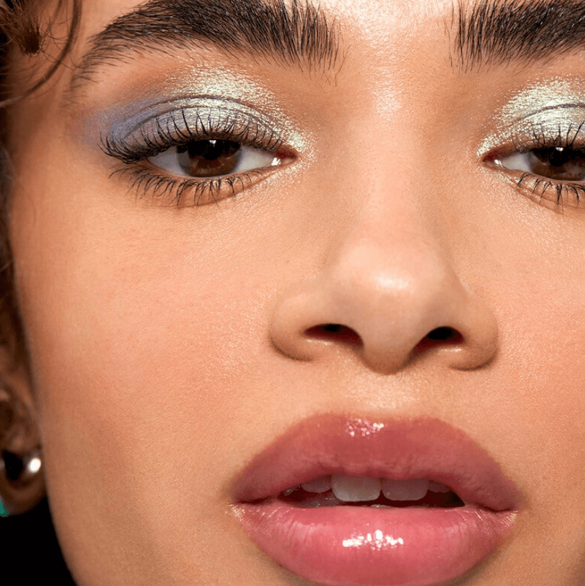 Close-up of a model showcasing glossy lips and shimmery eye makeup with e.l.f Glow Reviver Lip Oil.