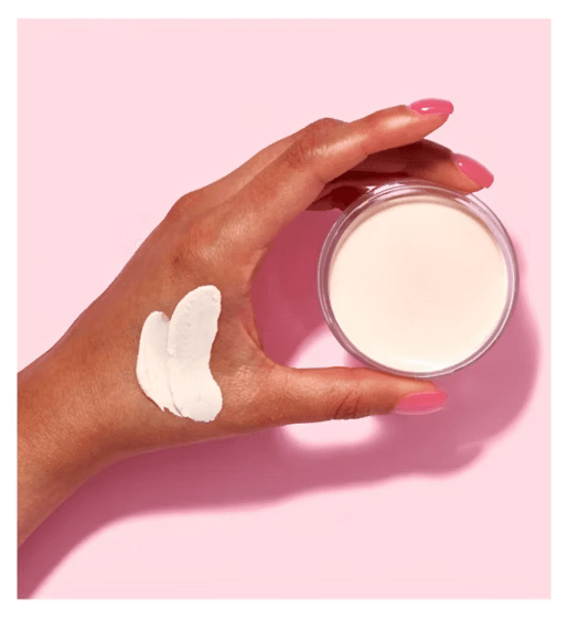 e.l.f Poreless Putty Primer Universal Sheer displayed on a hand, showcasing its creamy texture against a pink background.