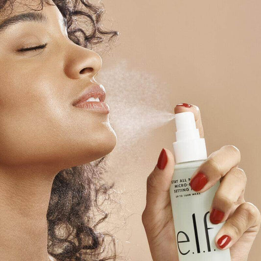 Woman applying e.l.f Stay All Night Micro-Fine Setting Mist for long-lasting makeup and hydration.