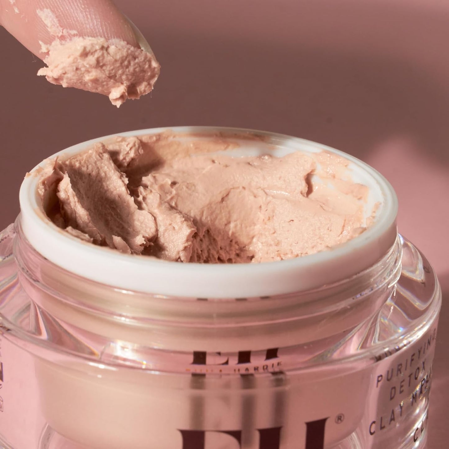 Jar of Emma Hardie pink clay product with a hand scooping out some of the clay.