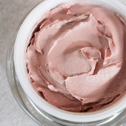Close-up of pink Emma Hardie cream in a glass bowl on a neutral background