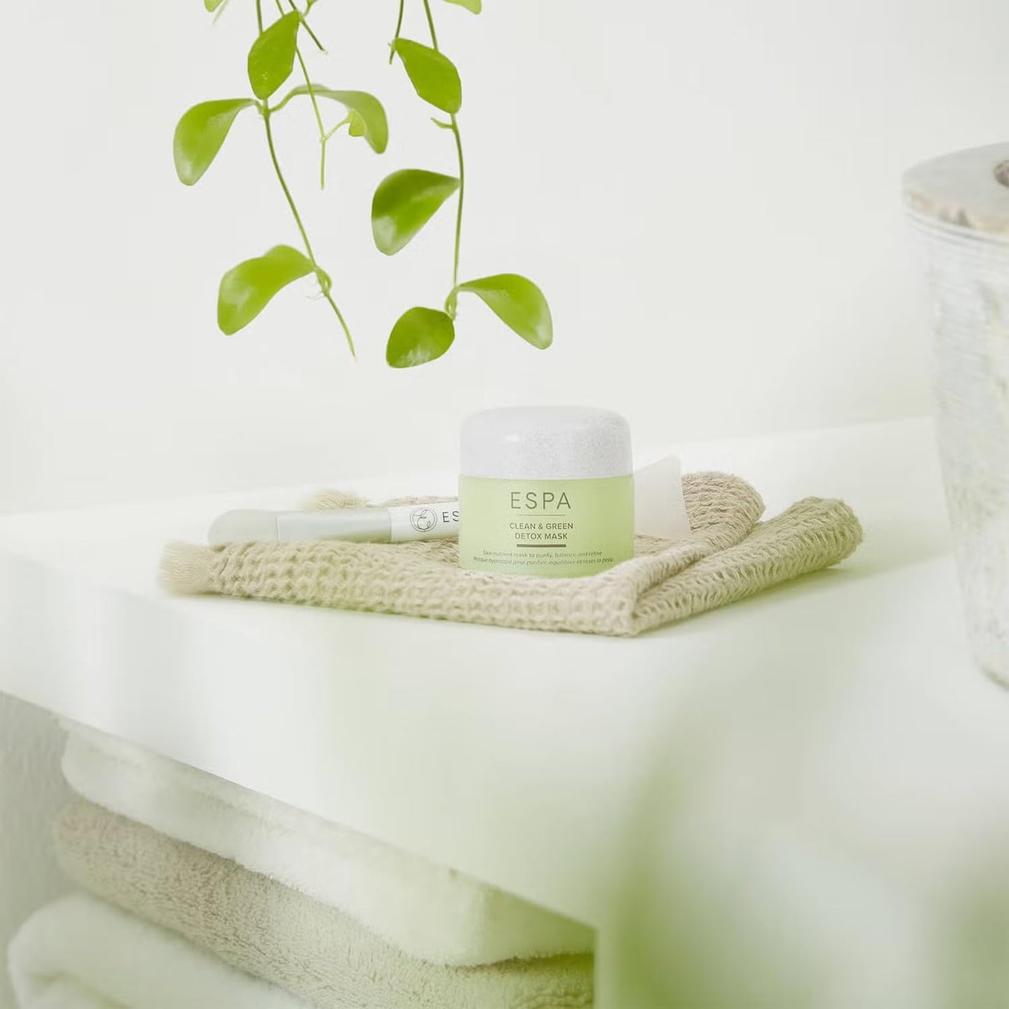 ESPA cream jar on a white surface with a plant in the background