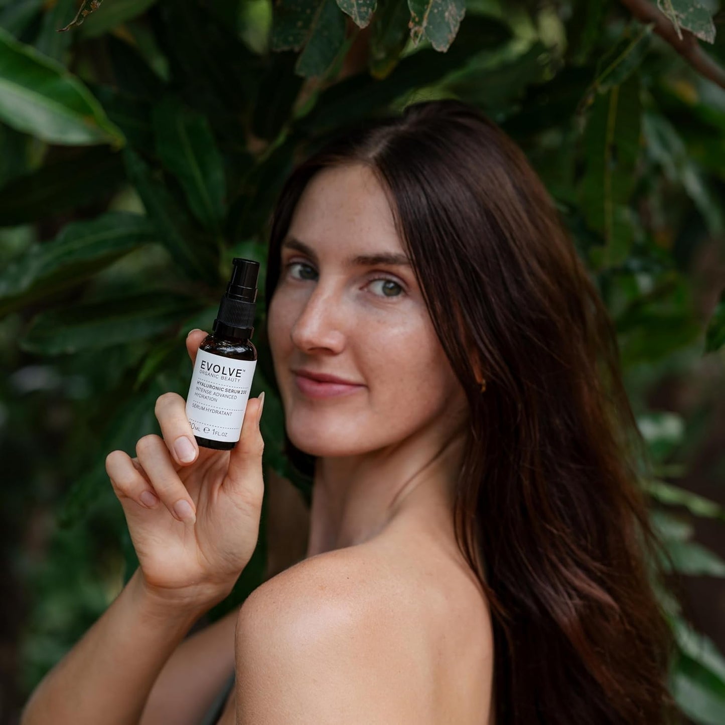 Woman holding a bottle labeled 'EVOLVE' against a green leafy background
