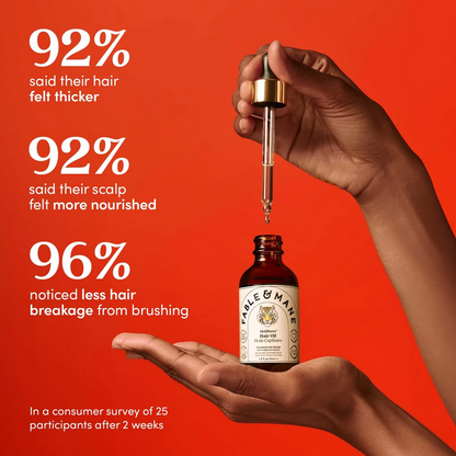 Hand holding a bottle of Fable & Mane hair oil with dropper against a red background, showing product benefits.
