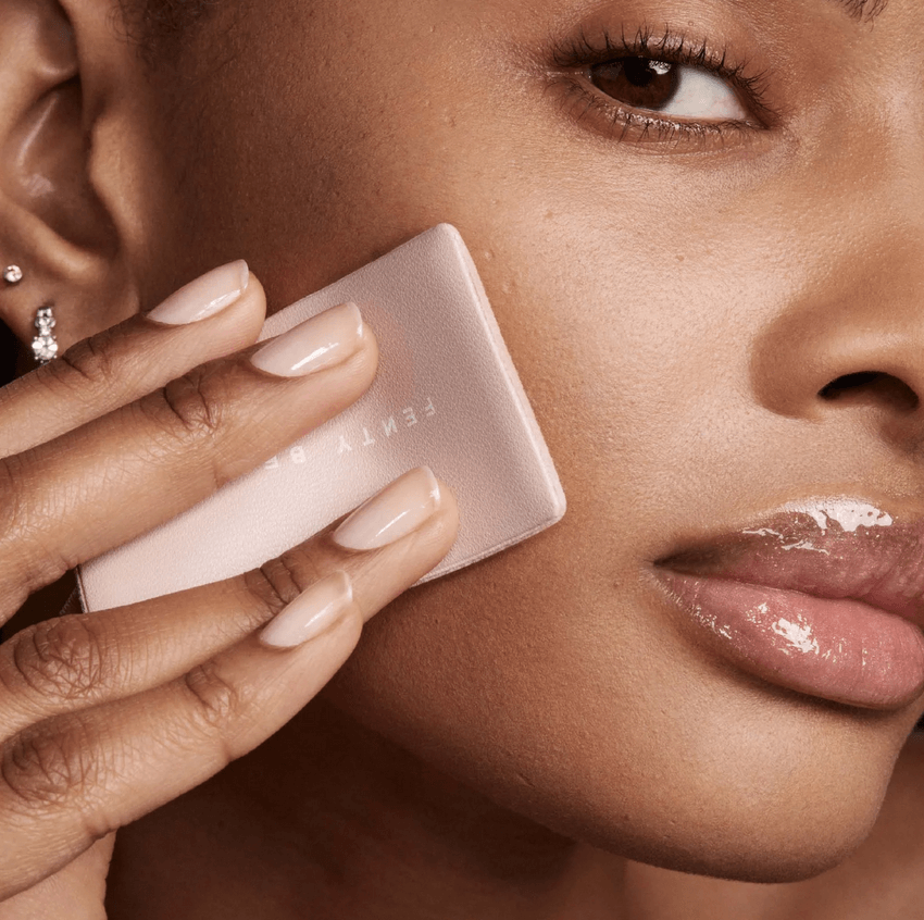 Model applying Fenty Beauty Mini Invisimatte Instant Setting Powder for a flawless matte finish.