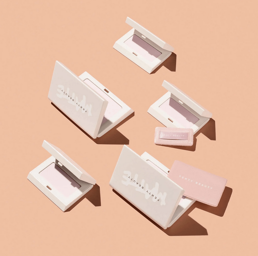 Fenty Beauty Mini Invisimatte Instant Setting + Blotting Powder scattered on a peach background, showcasing premium packaging.