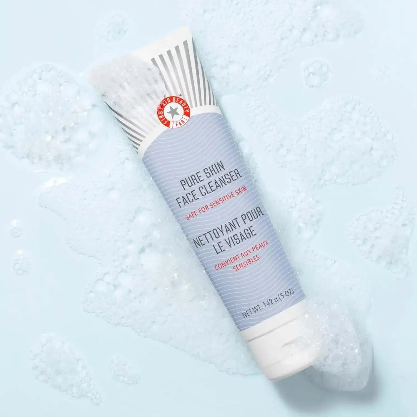 First Aid Beauty Face Cleanser 142g tube, gentle cleanser for sensitive skin, shown with foamy bubbles on a light surface.
