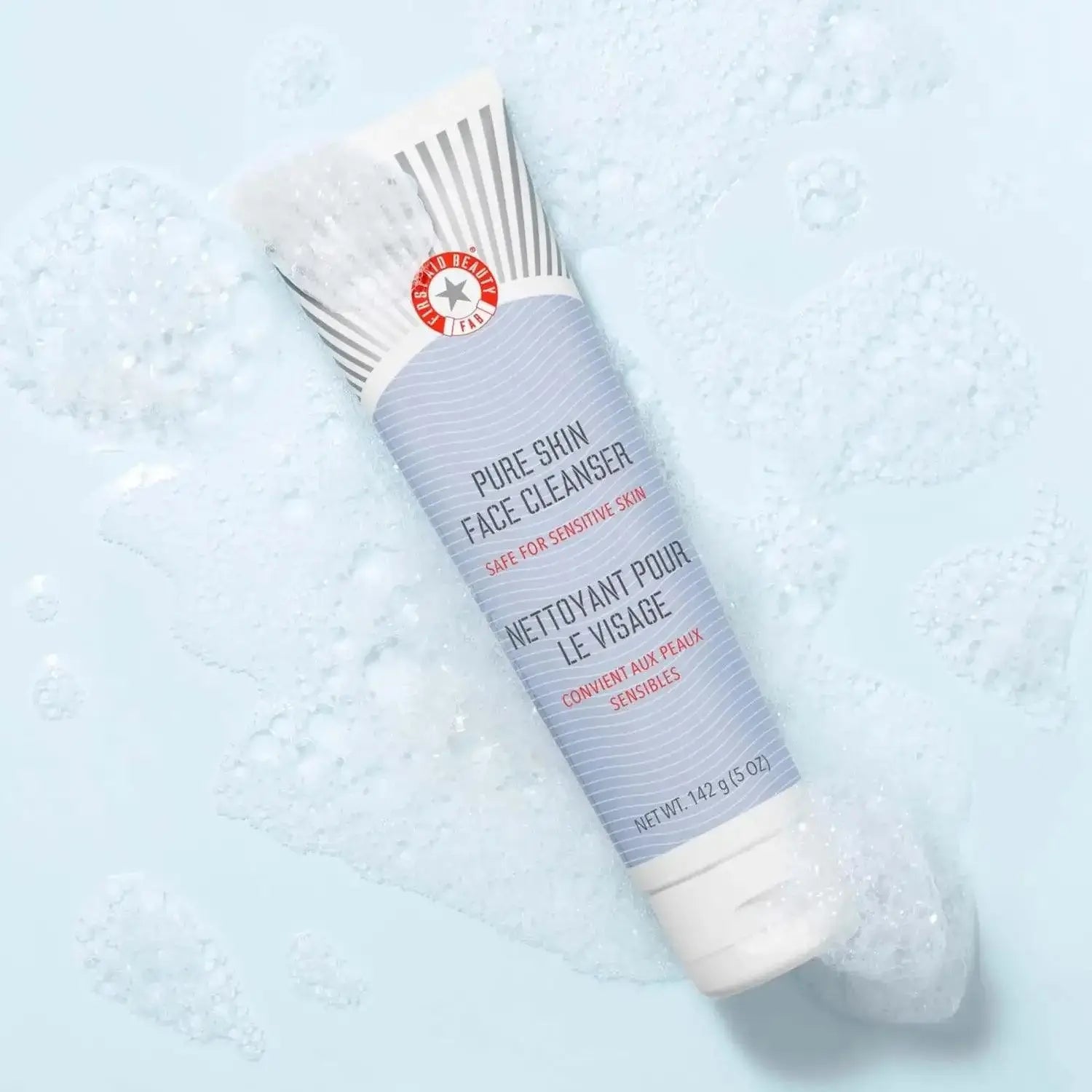 First Aid Beauty Face Cleanser 142g tube, gentle cleanser for sensitive skin, shown with foamy bubbles on a light surface.
