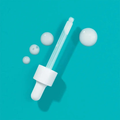 First Aid Beauty Facial Radiance Niacinamide Dark Spot Serum dropper and serum bubbles on a turquoise background.