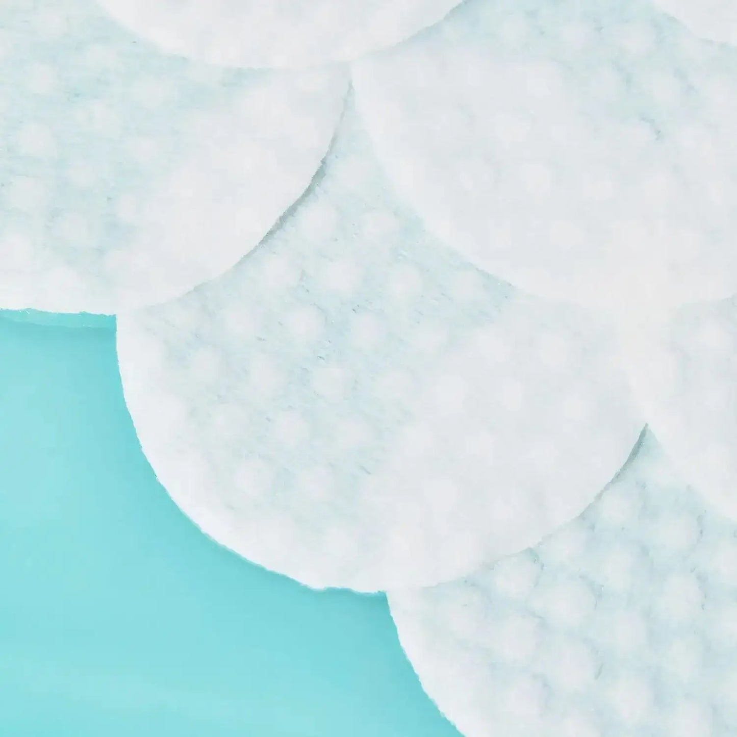 Close-up of First Aid Beauty Facial Radiance Pads on a blue background, showcasing their textured surface.