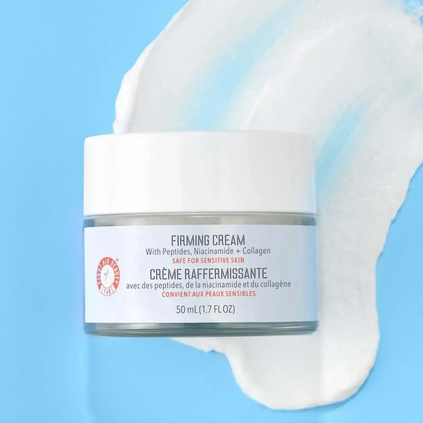 First Aid Beauty Firming Cream with Peptides, Niacinamide + Collagen 50ml in jar against a blue background.