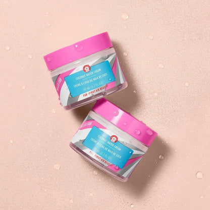 First Aid Beauty Hello Fab Coconut Water Cream jars on a pink background, offering hydration and moisture for the skin.