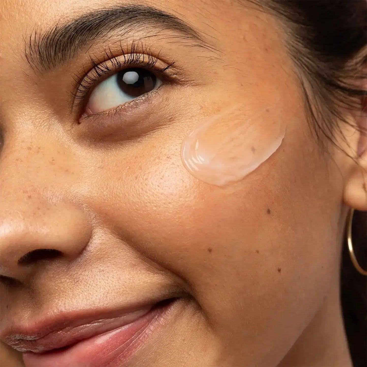 Woman applying First Aid Beauty Hello Fab Coconut Water Cream on her cheek for hydration and nourishment.