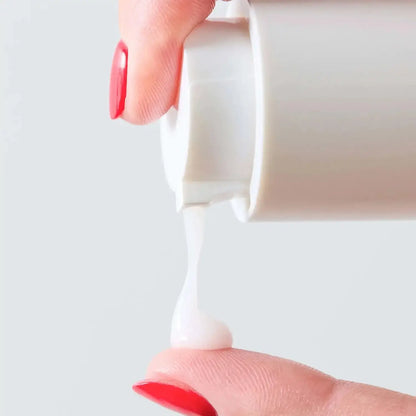 First Aid Beauty Hydrating Serum with Hyaluronic Acid being dispensed onto a fingertip, showcasing its creamy texture.