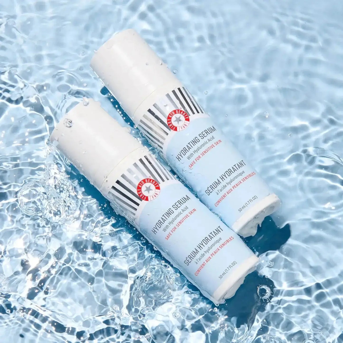 First Aid Beauty Hydrating Serum with Hyaluronic Acid bottles on water background, showcasing skincare product innovation.
