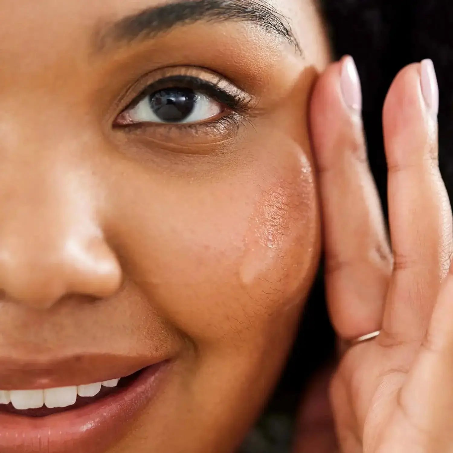 Close-up of a woman applying First Aid Beauty Hydrating Serum with Hyaluronic Acid for radiant, moisturized skin.