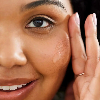 Close-up of a woman applying First Aid Beauty Hydrating Serum with Hyaluronic Acid for radiant, moisturized skin.