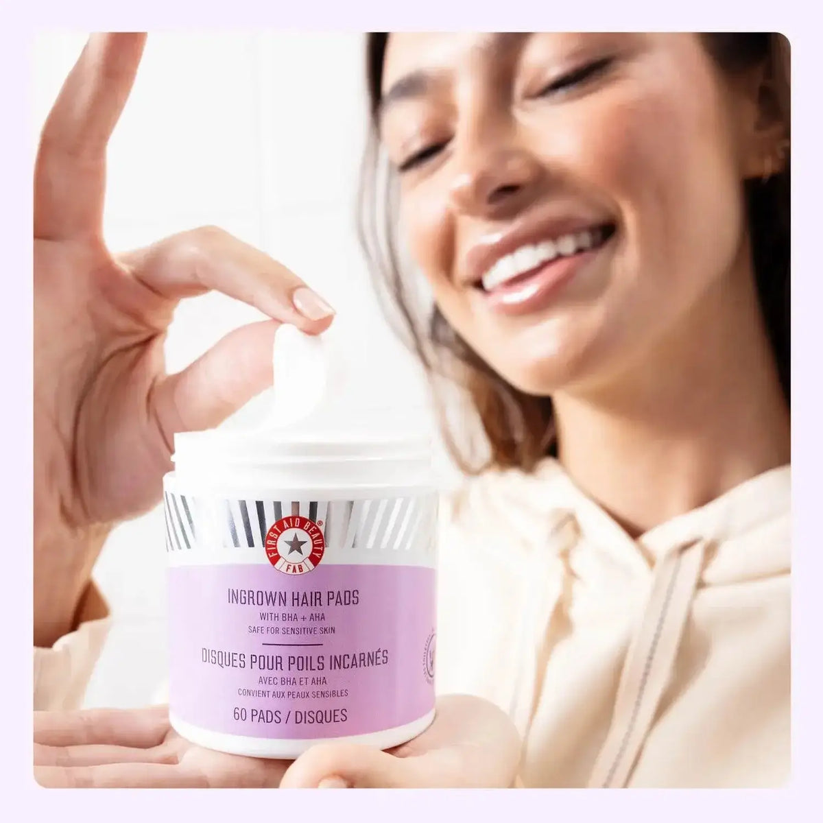 First Aid Beauty Ingrown Hair Treatment Pads displayed by smiling woman, promoting skin clarity and reduced razor bumps.